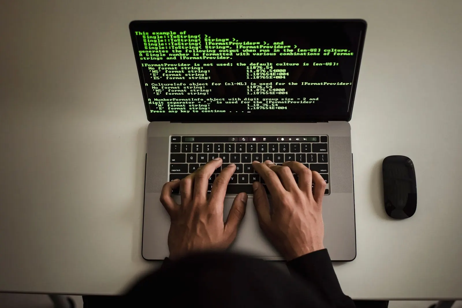 Hands typing on a laptop displaying programming code.